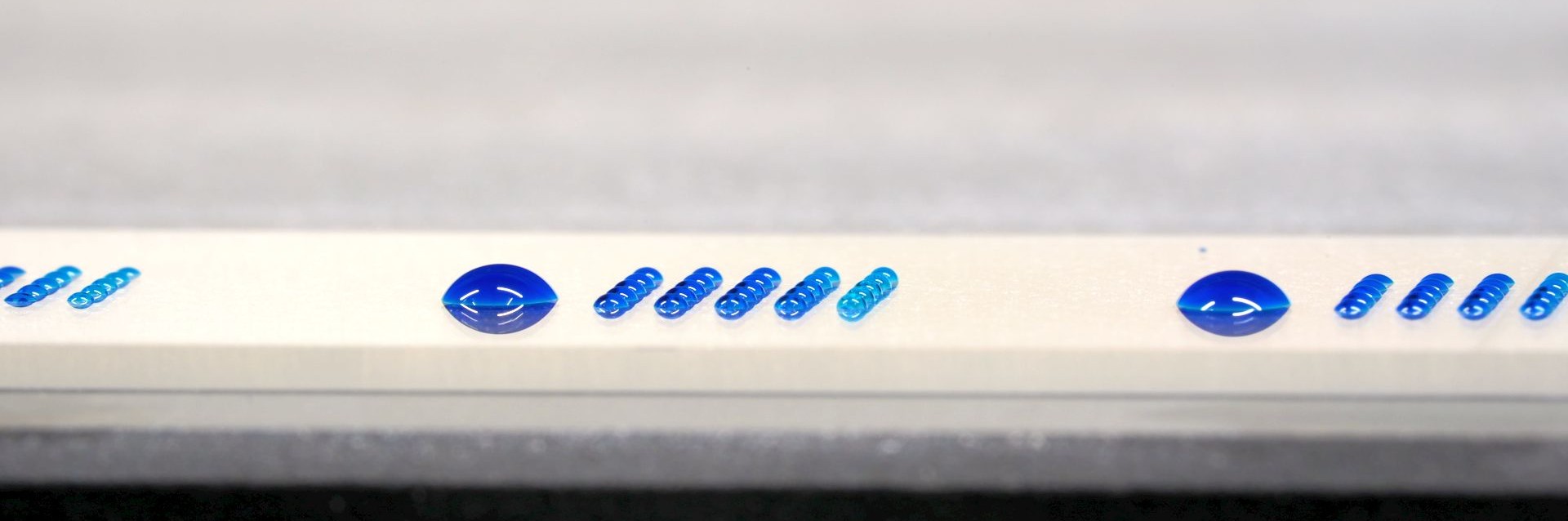 nanoliter microarray next to microliter droplets on a microscope slide to show the difference in size
